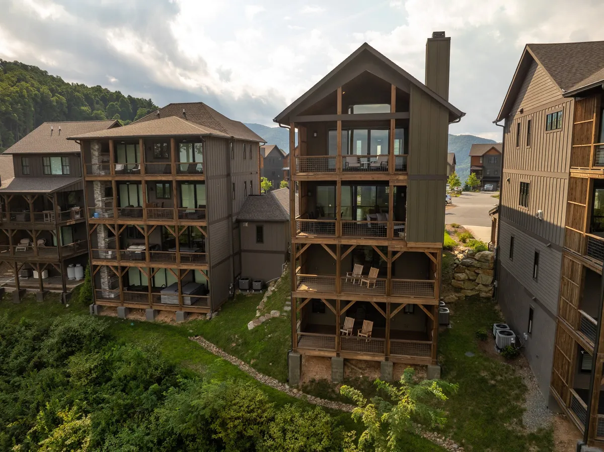 A multi-story building with spacious wooden balconies overlooks the surrounding greenery, offering inviting spaces for relaxing, gathering, or enjoying the mountain scenery. The mood is serene and welcoming, perfectly suited for family bonding moments.