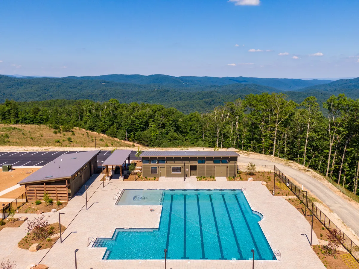 This exterior image showcases a sparkling swimming pool and recreation area surrounded by mountains. The mood is tranquil and relaxed, with clear evidence of communal amenities ideal for family fun and social gatherings.