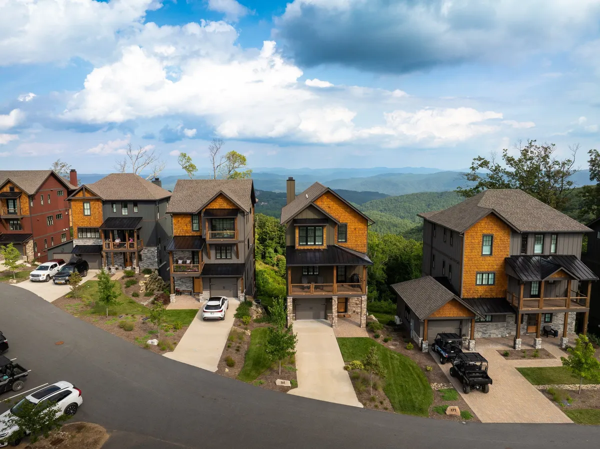 This exterior image captures modern mountain homes nestled amid lush greenery, with an expansive mountain view forming a breathtaking backdrop. The environment is vibrant and inviting, conveying a sense of adventure and connection to nature.